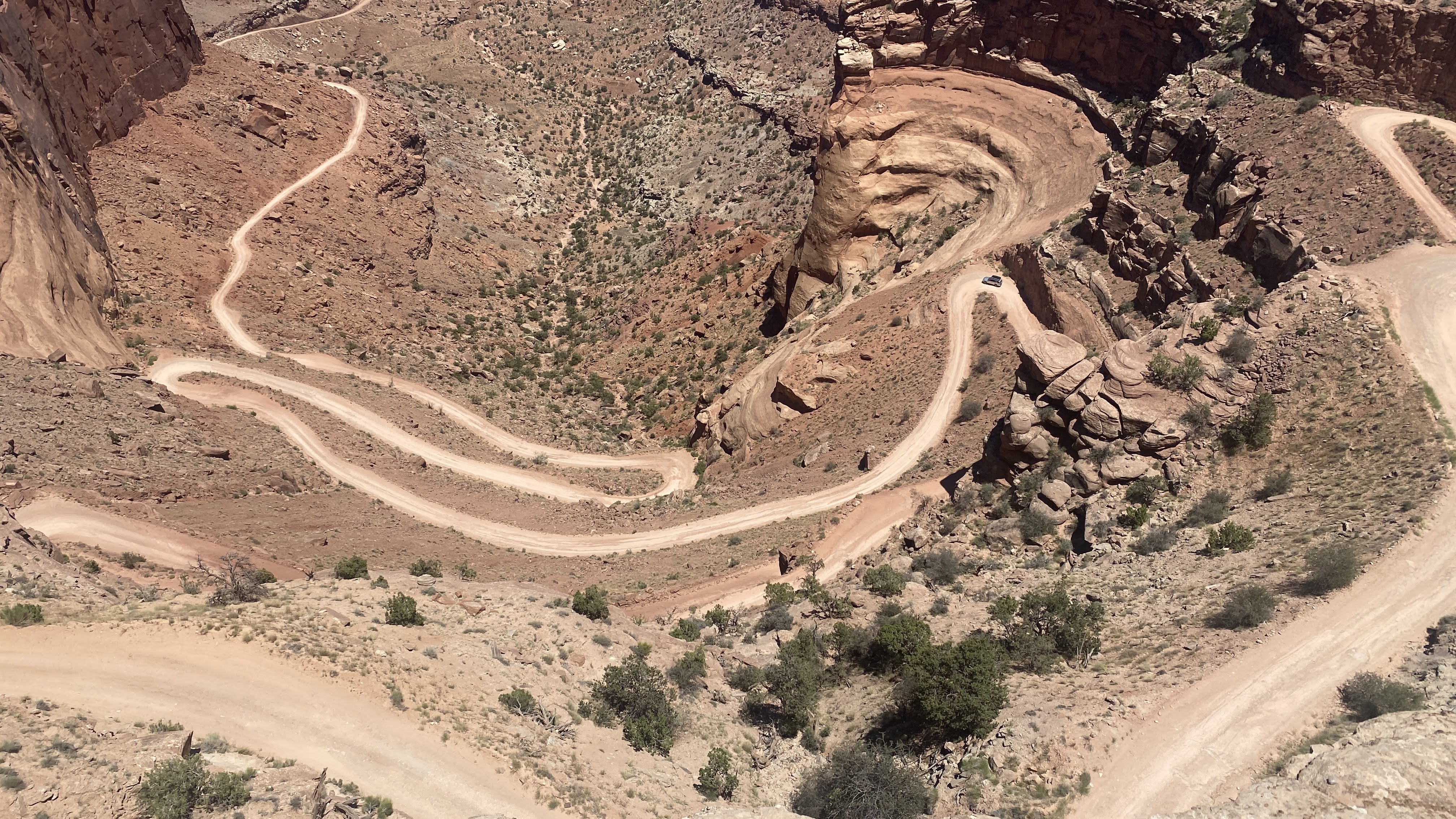 A winding dirt road cutting through a rocky desert canyon